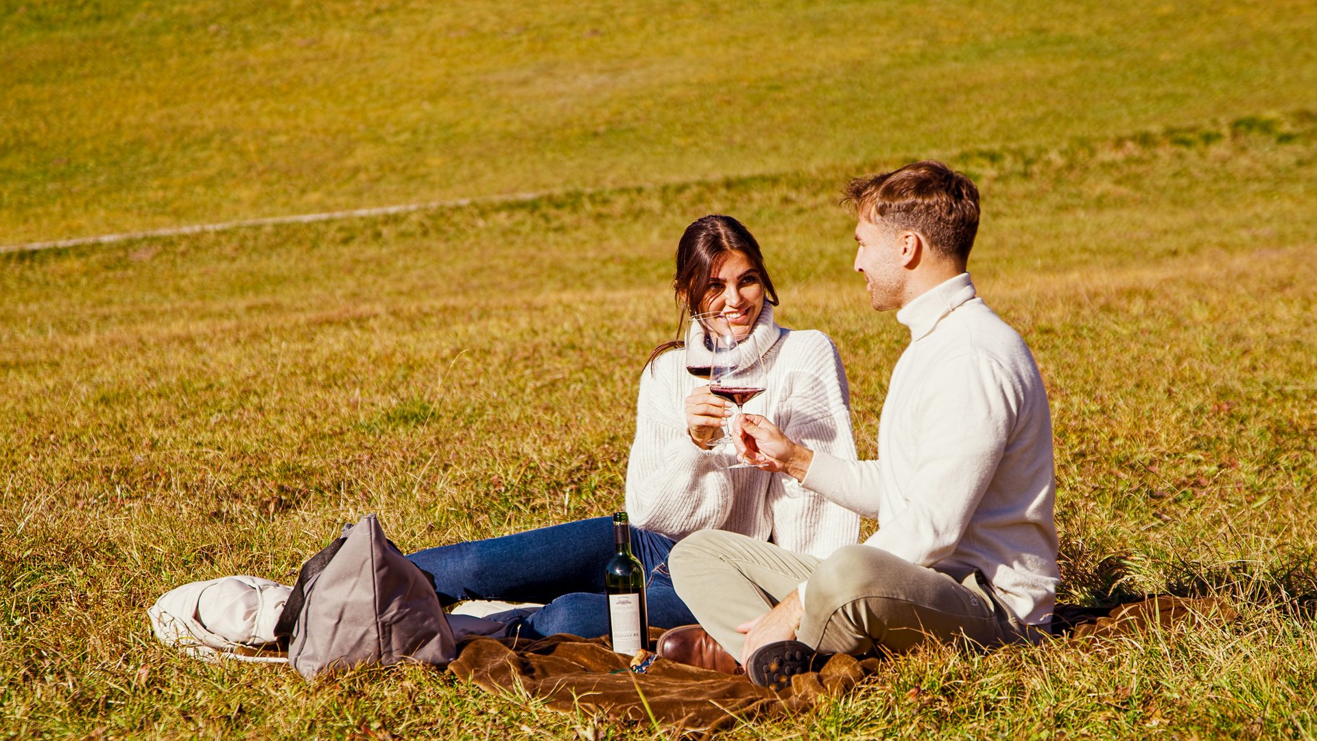 Hotel Sonnenhof Couple sitting on grass toasting with red wine glasses
