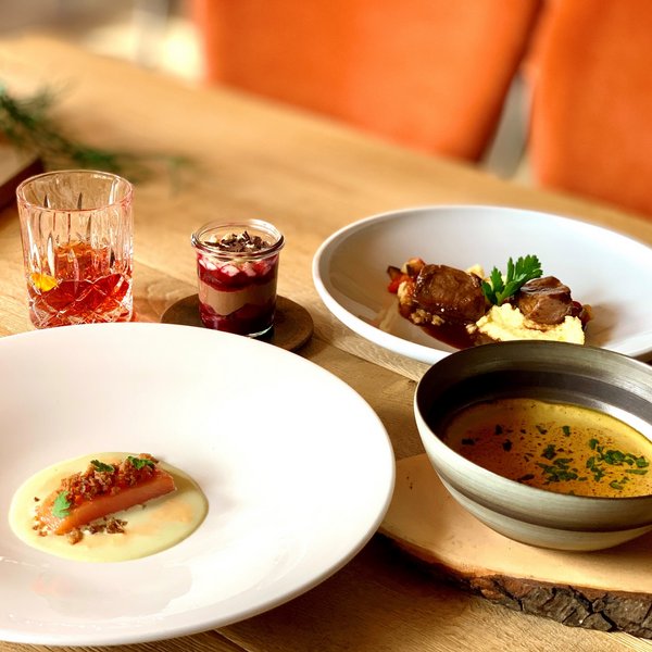 Hotel Sonnenhof Vorspeise, Suppe, Hauptspeise, Dessert und Drink auf rustikalem Holztisch angerichtet