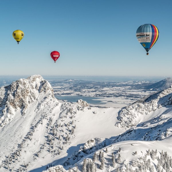 Hotel Sonnenhof Mehrere bunte Heißluftballons über verschneiten Bergen bei klarem Himmel