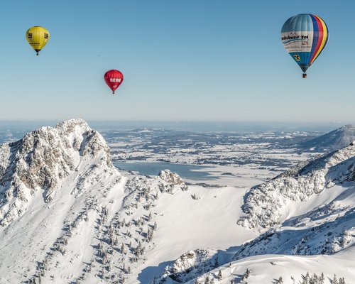 Hotel Sonnenhof Mehrere bunte Heißluftballons über verschneiten Bergen bei klarem Himmel