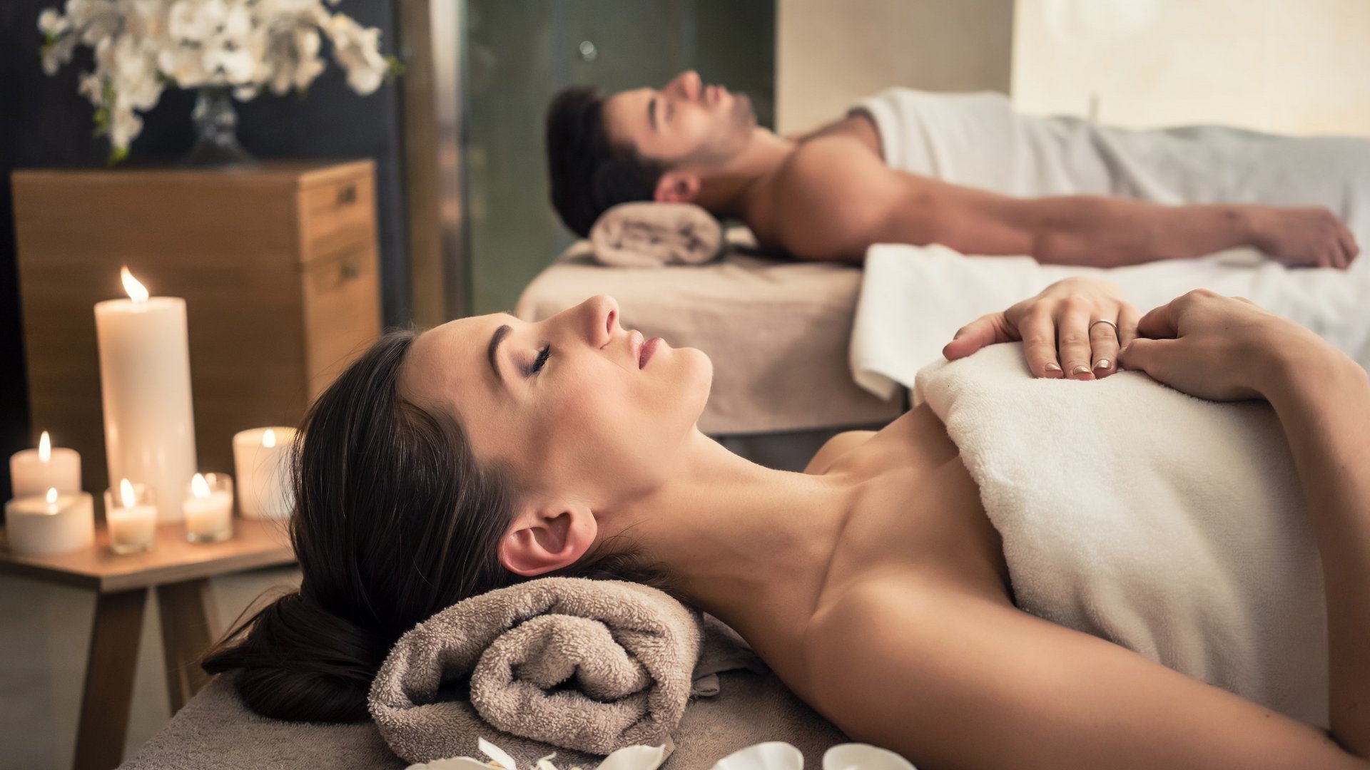 Hotel Sonnenhof Paar entspannt bei Paarmassage im Spa mit Kerzen und Blumen