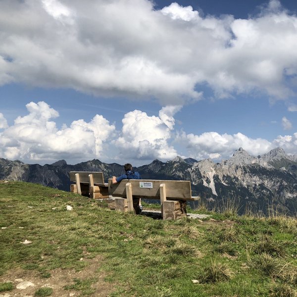 Hotel Sonnenhof Person sitzt auf Bank mit Blick auf Berglandschaft und bewölkten Himmel