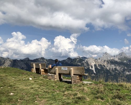 Hotel Sonnenhof Person sitzt auf Bank mit Blick auf Berglandschaft und bewölkten Himmel