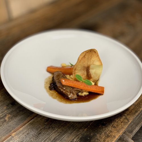 Hotel Sonnenhof Fein angerichtetes Gericht mit Fleisch, Karotten und einer Chip-Garnitur auf einem weißen Teller