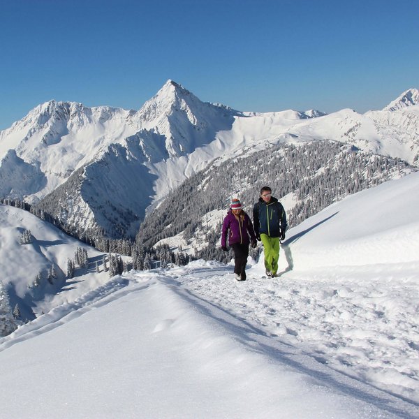 Hotel Sonnenhof Zwei Personen wandern auf verschneitem Pfad in den Bergen bei klarem Himmel