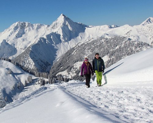 Hotel Sonnenhof Zwei Personen wandern auf verschneitem Pfad in den Bergen bei klarem Himmel