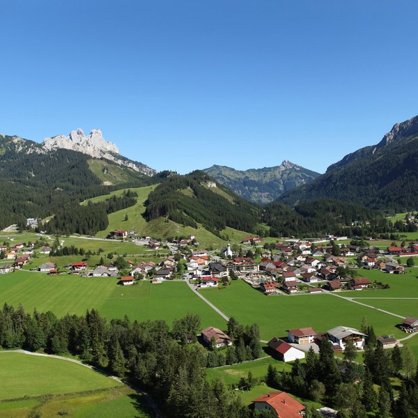 Hotel Sonnenhof Panoramablick auf ein Dorf in einem grünen Tal mit Bergen im Hintergrund