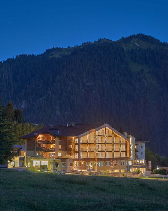 Hotel Sonnenhof Lit hotel building with mountain backdrop at night
