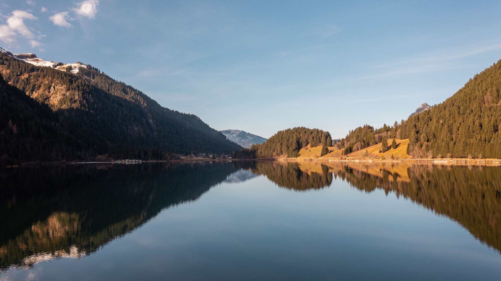 Hotel Sonnenhof Bergsee mit klarer Spiegelung von bewaldeten Hängen und blauem Himmel
