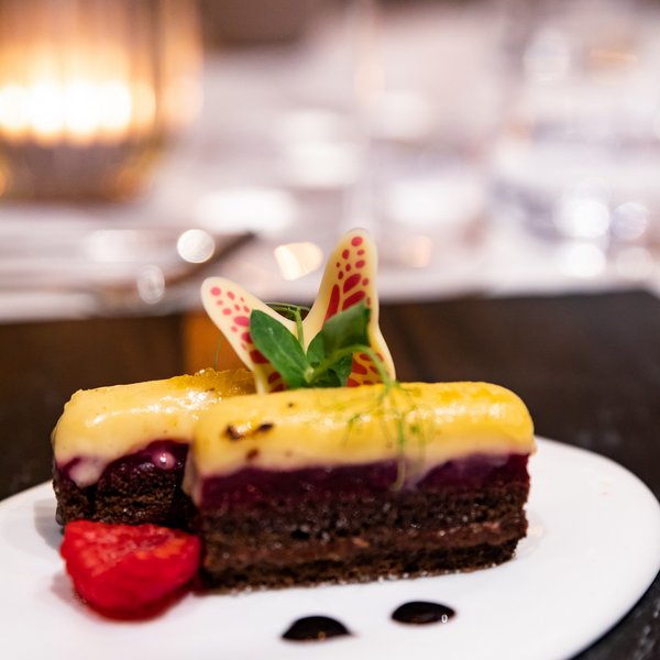 Hotel Sonnenhof Chocolate dessert with yellow cream, raspberry, and chocolate decoration on white plate