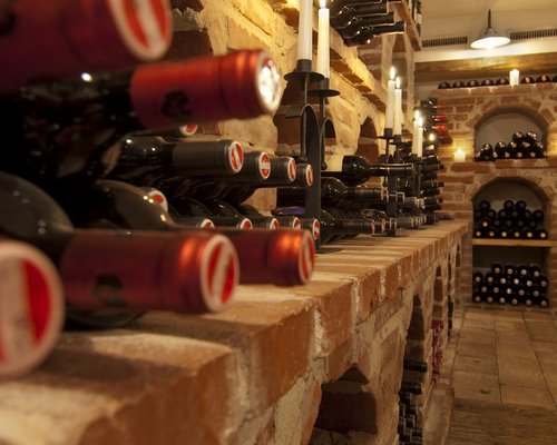 Hotel Sonnenhof Weinkeller mit roten Weinflaschen auf Ziegelregalen und brennenden Kerzen