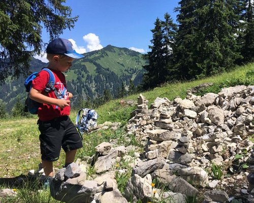 Hotel Sonnenhof Junge mit rotem T-Shirt schaut auf Steinmännchen am Bergweg bei sonnigem Wetter