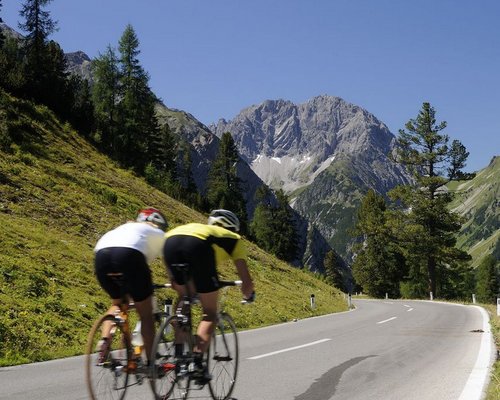 Hotel Sonnenhof Zwei Radfahrer auf Bergstraße mit Alpen und blauem Himmel