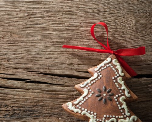 Hotel Sonnenhof Lebkuchen in Tannenbaumform mit weißer Verzierung und rotem Band auf Holz