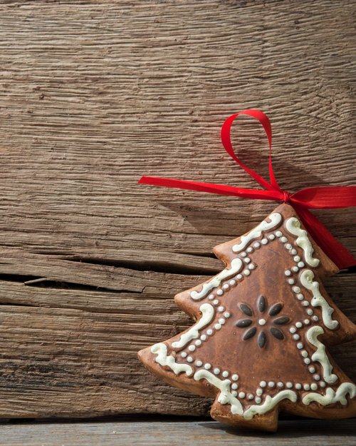 Hotel Sonnenhof Lebkuchen in Tannenbaumform mit weißer Verzierung und rotem Band auf Holz