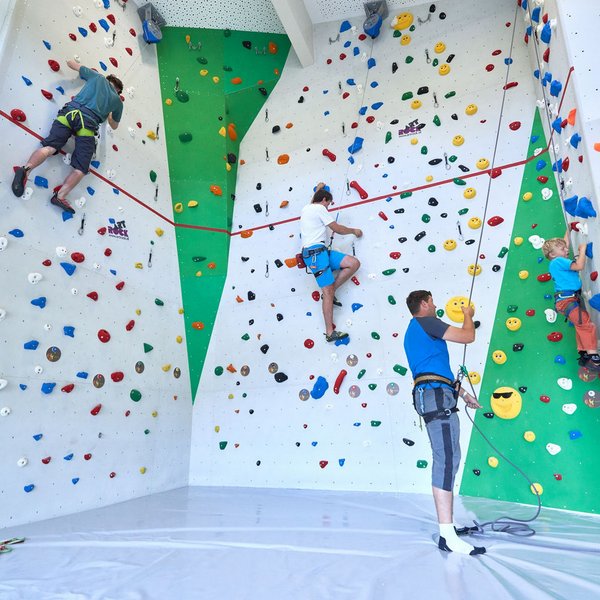 Hotel Sonnenhof Menschen klettern an einer Indoor-Kletterwand mit bunten Griffen