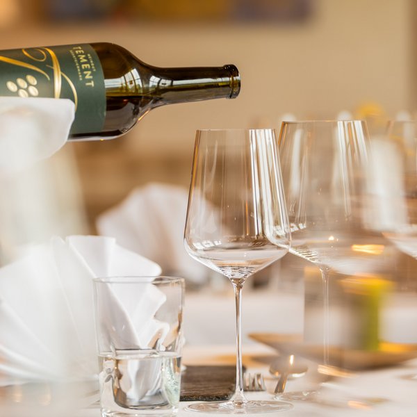 Hotel Sonnenhof Weinflasche wird in ein Weinglas an festlich gedecktem Tisch eingeschenkt