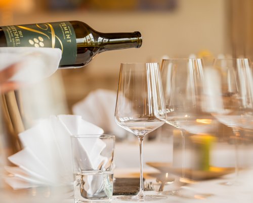 Hotel Sonnenhof Weinflasche wird in ein Weinglas an festlich gedecktem Tisch eingeschenkt