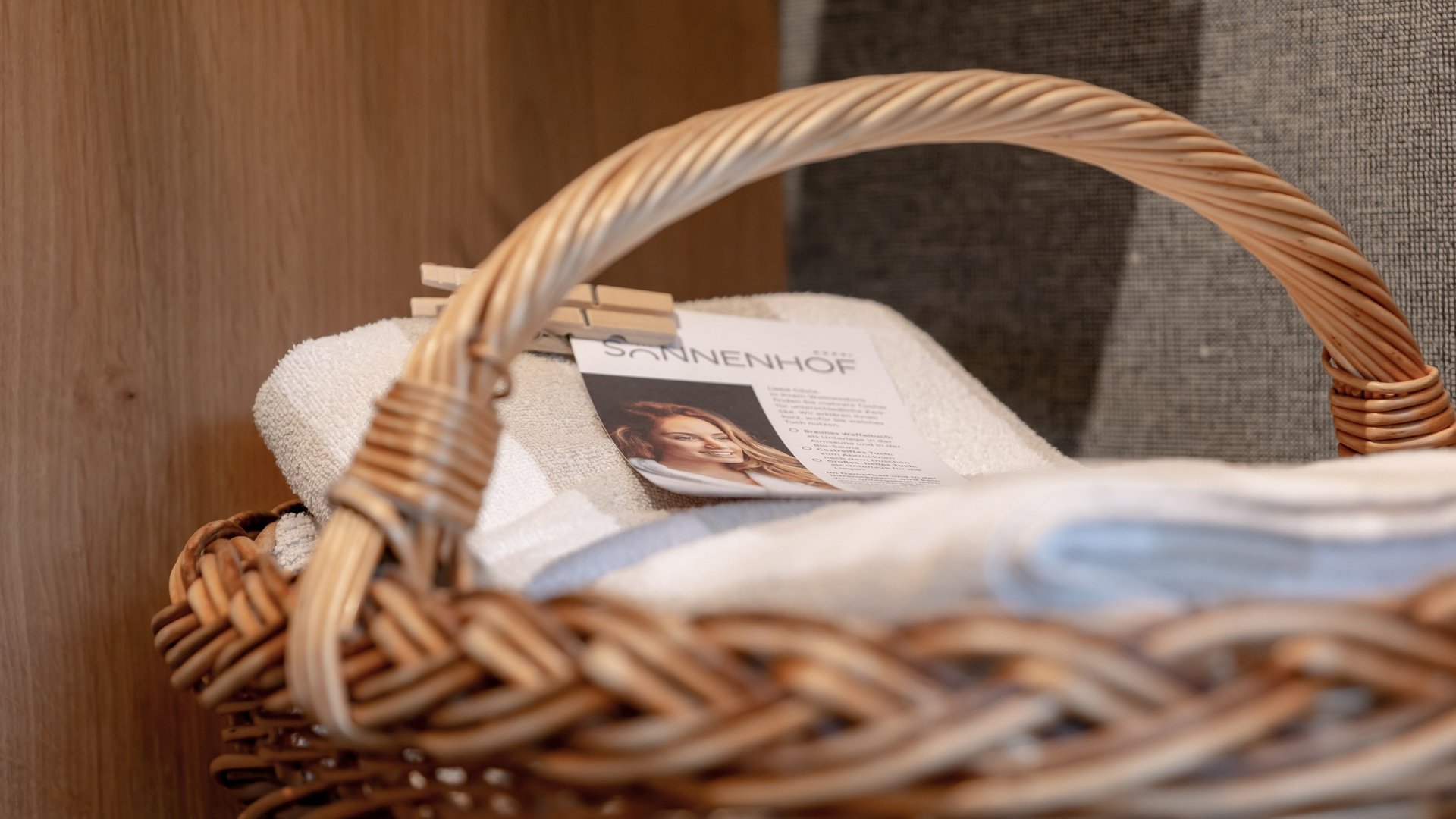 Hotel Sonnenhof Wicker basket with white towels and a card featuring a woman’s picture