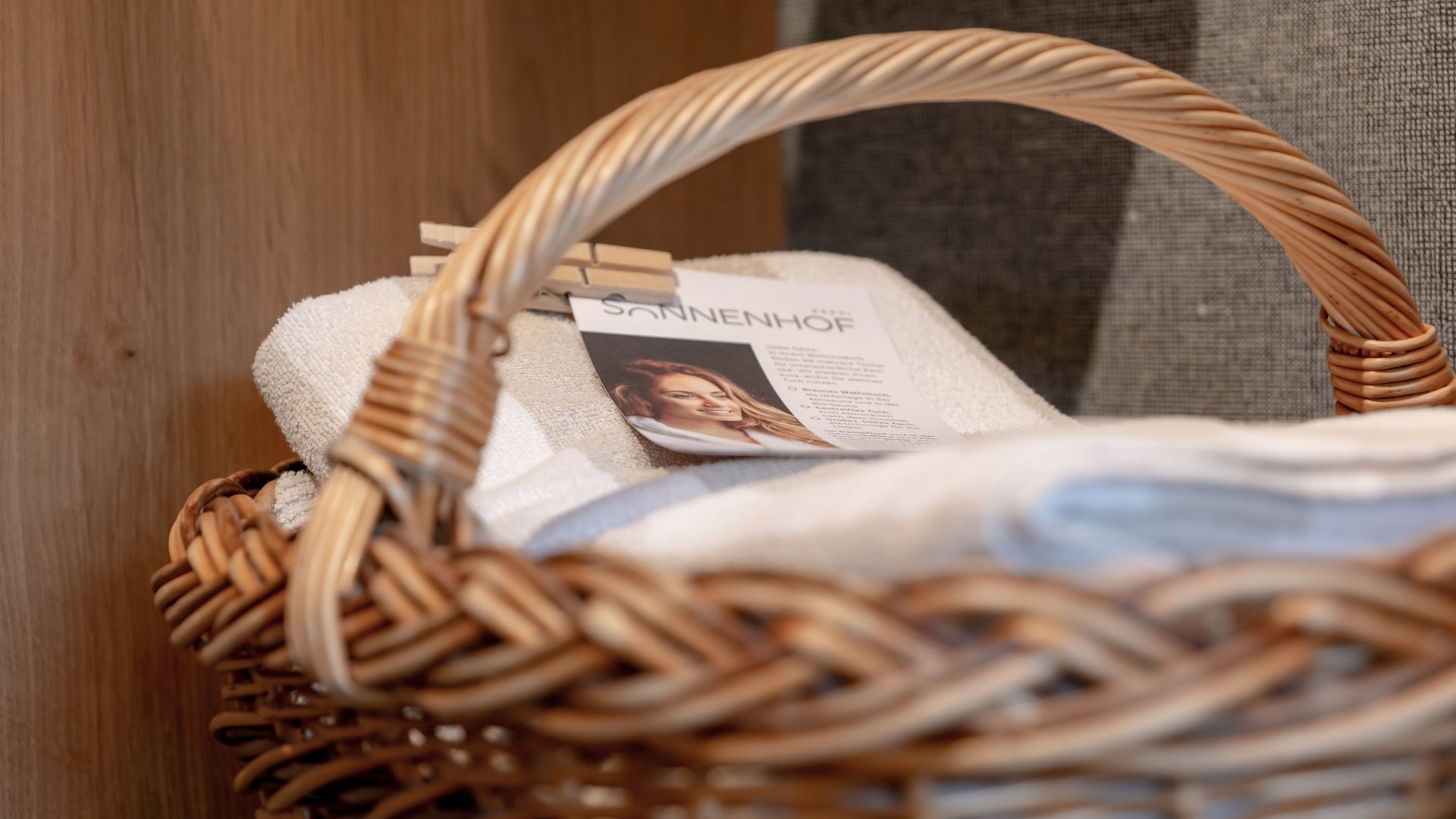 Hotel Sonnenhof Wicker basket with white towels and a card featuring a woman’s picture