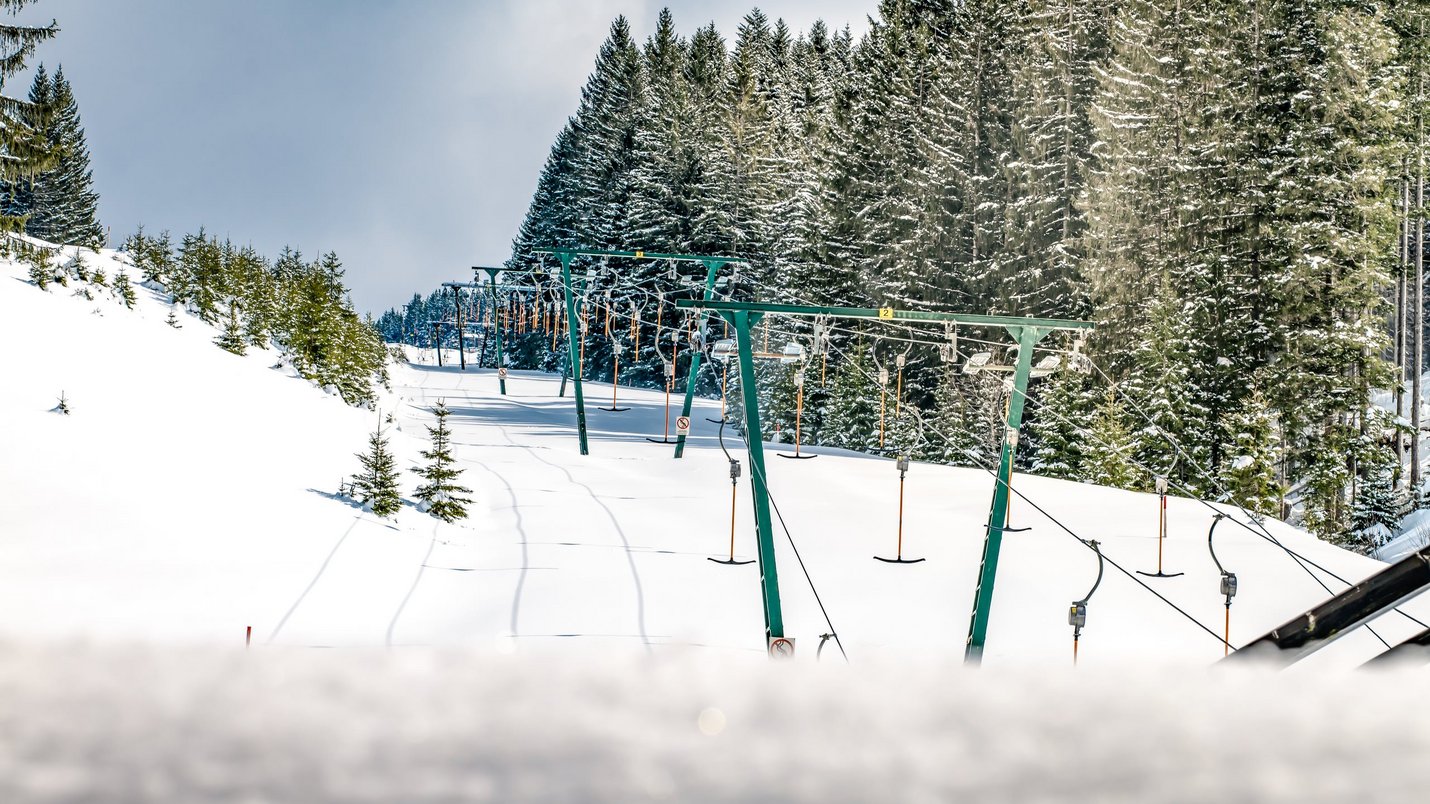 Hotel Sonnenhof Skilift auf schneebedeckter Piste neben einem Wald mit verschneiten Bäumen