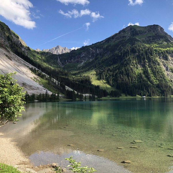 Hotel Sonnenhof Klarer Bergsee mit grünen Hängen und blauem Himmel