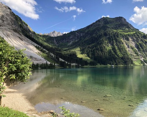 Hotel Sonnenhof Klarer Bergsee mit grünen Hängen und blauem Himmel