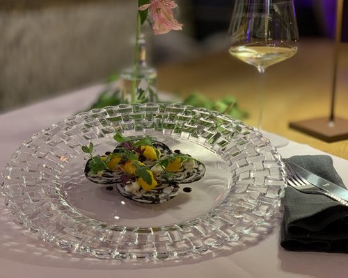 Hotel Sonnenhof Fein angerichtetes Gericht mit Garnitur auf transparentem Glassteller mit Besteck und Glas