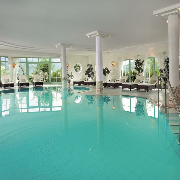 Hotel Sonnenhof Hallenbad mit Liegestühlen und großen Fenstern mit Bergblick