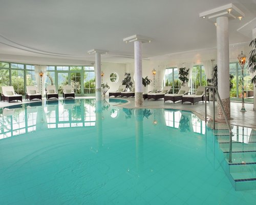 Hotel Sonnenhof Hallenbad mit Liegestühlen und großen Fenstern mit Bergblick