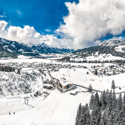 Hotel Sonnenhof Verschneite Alpenlandschaft mit Dorf, Wäldern und Bergen unter blauem Himmel