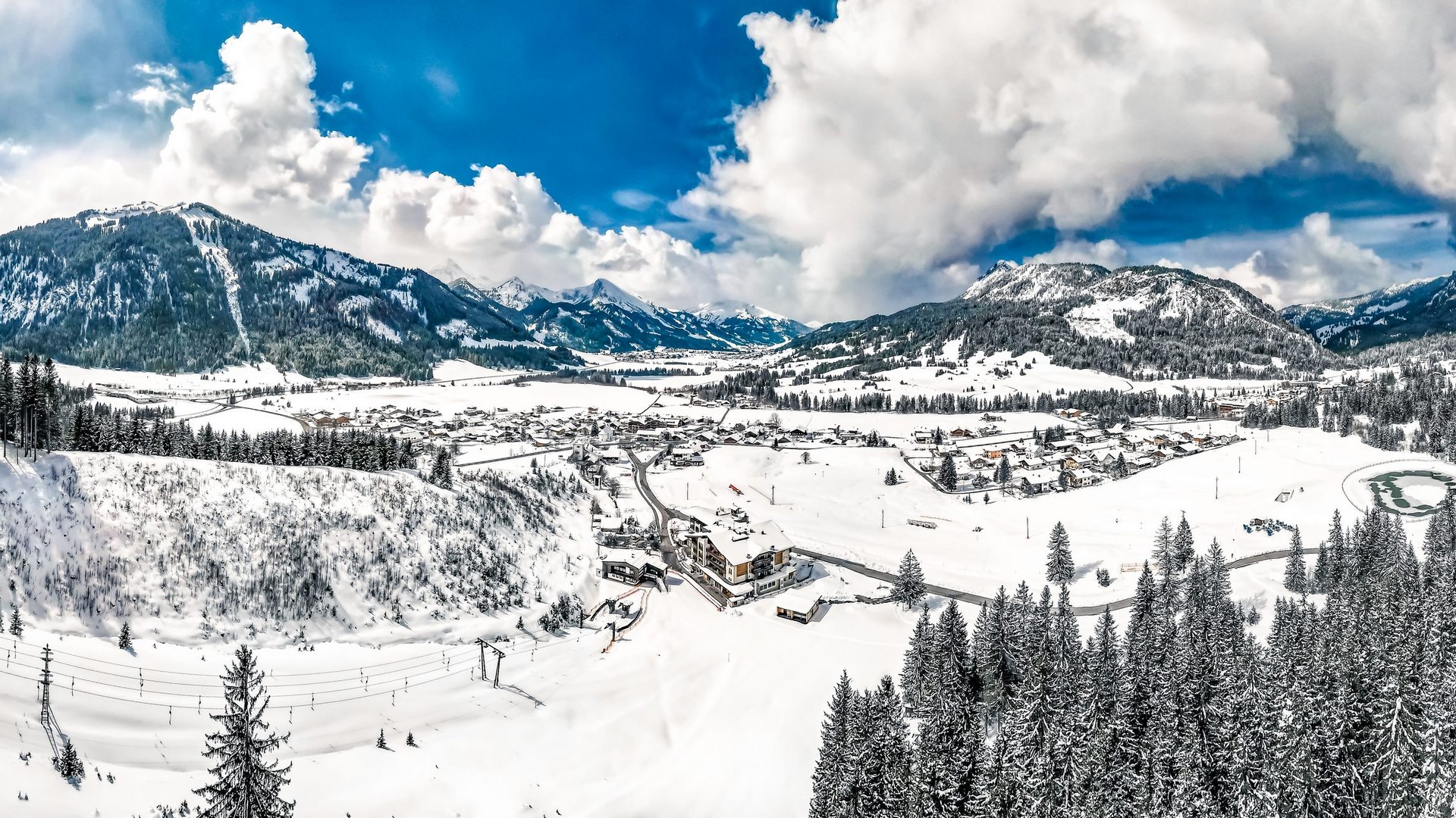 Hotel Sonnenhof Verschneite Alpenlandschaft mit Dorf, Wäldern und Bergen unter blauem Himmel