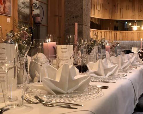 Hotel Sonnenhof Festlich gedeckter Tisch mit Servietten, Kerzen und Gläsern in rustikalem Raum