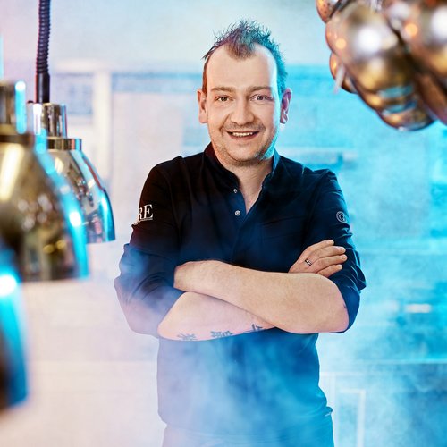 Hotel Sonnenhof Smiling chef with crossed arms in a steamy kitchen