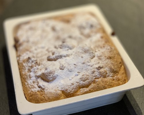 Hotel Sonnenhof Frischer gebackener Kuchen in weißer Backform mit Puderzucker bestreut