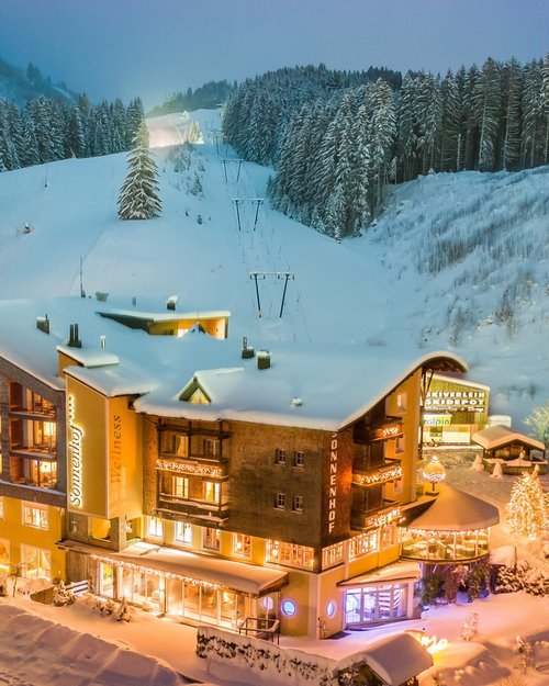 Hotel Sonnenhof Winterliches Hotel am Skihang mit beleuchteten Fenstern und verschneiten Bäumen