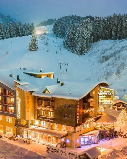 Hotel Sonnenhof Winter hotel by ski slope with lit windows and snow-covered trees