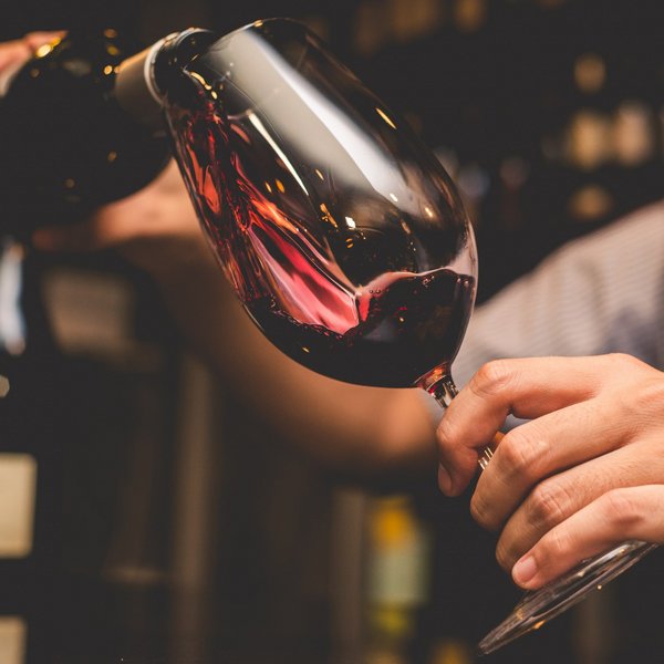Hotel Sonnenhof Mann gießt Rotwein in ein Weinglas in einer Bar