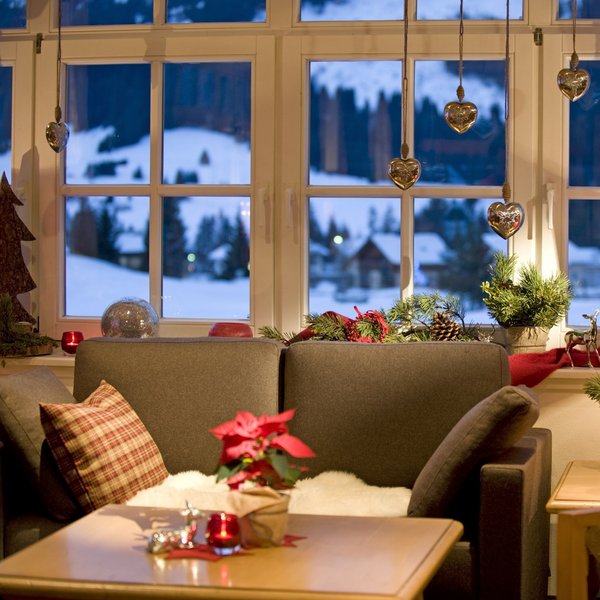 Hotel Sonnenhof Gemütliches Wohnzimmer mit Weihnachtsdekoration und Blick auf verschneite Landschaft