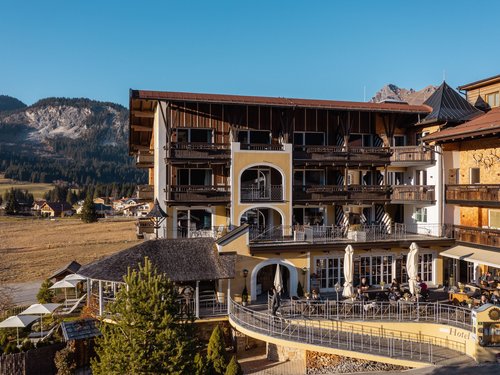 Hotel Sonnenhof Hotel building with terrace and mountain backdrop on a sunny day