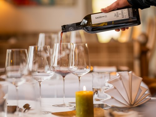 Hotel Sonnenhof Wine being poured into a glass at a finely set restaurant table