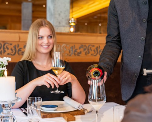 Hotel Sonnenhof Frau mit Weißweinglas im Restaurant während Kellner Wein einschenkt