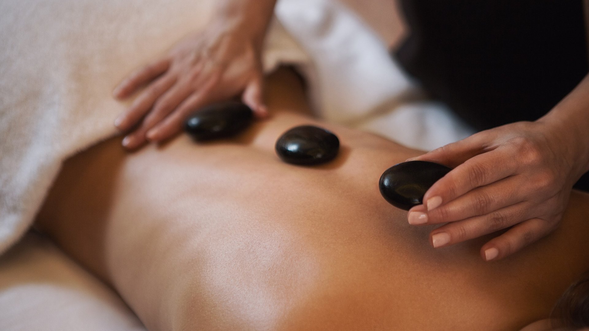 Hotel Sonnenhof Person erhält Hot-Stone-Massage auf nacktem Rücken