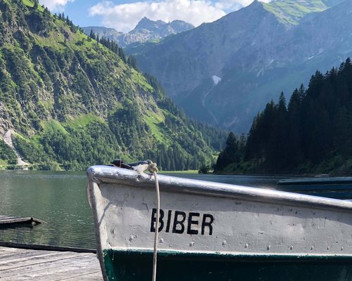 Hotel Sonnenhof Boot Biber auf See mit grünen Bergen und blauem Himmel im Hintergrund