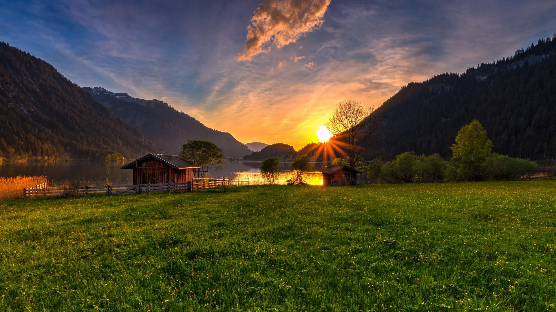 Hotel Sonnenhof Sonnenuntergang über einem See mit Hütten und grüner Wiese im Tal