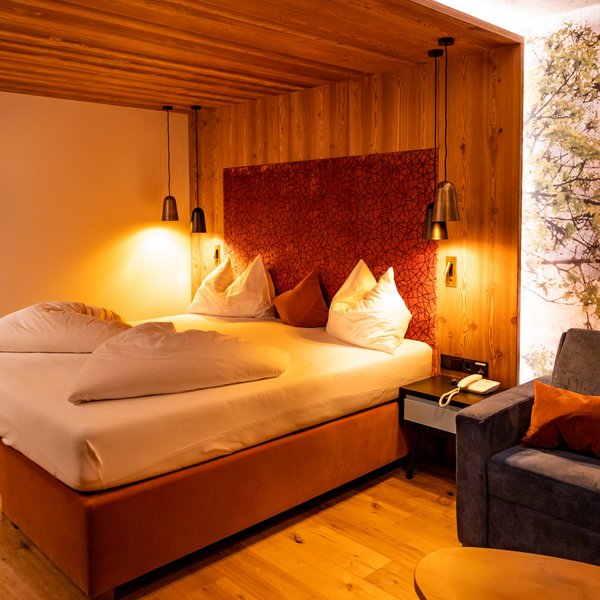 Hotel Sonnenhof Cozy bedroom with large bed, wood paneling, and seating area
