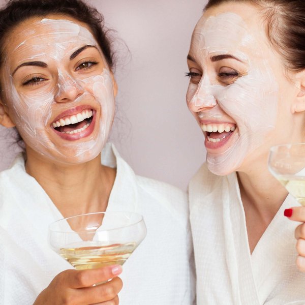 Hotel Sonnenhof Zwei Frauen mit Gesichtsmaske in Bademänteln die mit einem Drink lachen