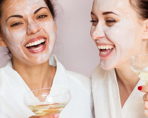 Hotel Sonnenhof Zwei Frauen mit Gesichtsmaske in Bademänteln die mit einem Drink lachen