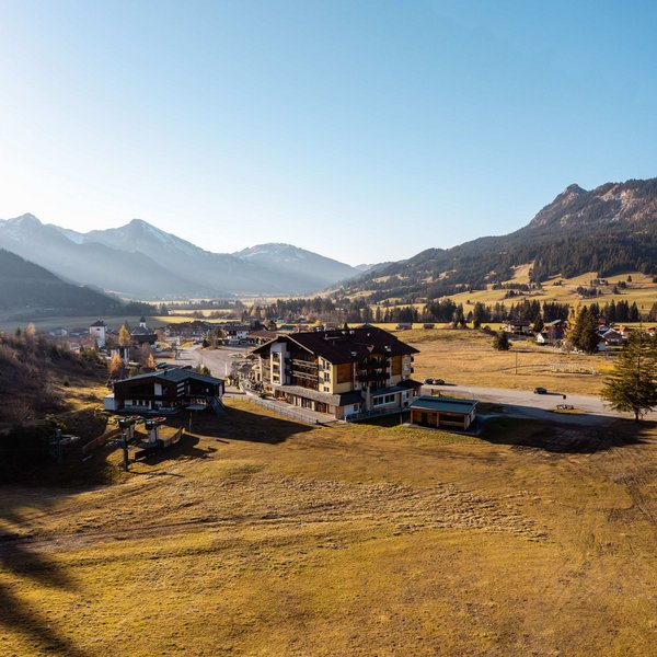 Hotel Sonnenhof Village with mountains in background and open fields under clear sky