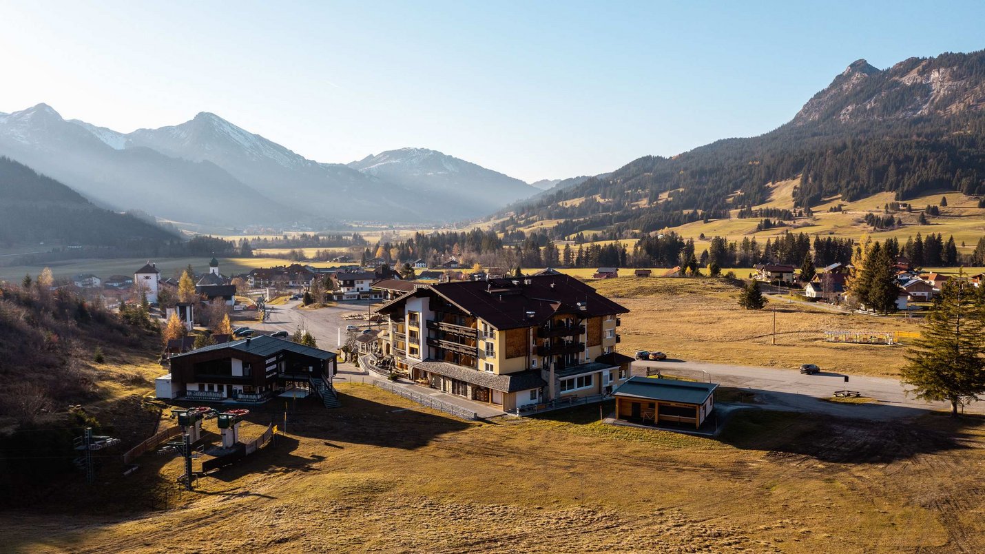 Hotel Sonnenhof Dorf mit Bergen im Hintergrund und offenen Feldern unter klarem Himmel